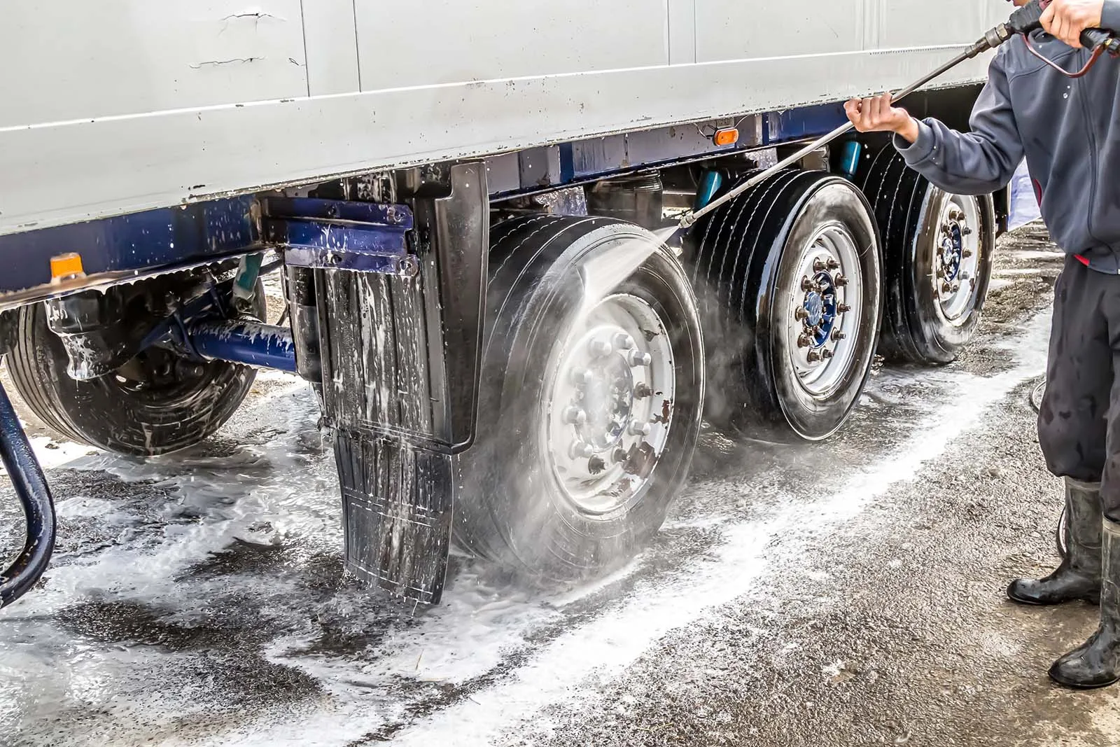 Pressure washing road film from a trailer chassis and wheels